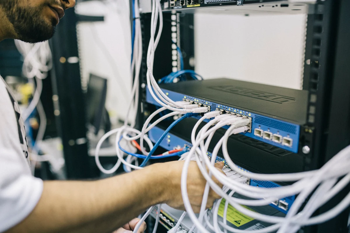 Technicien intervenant sur les connexions d’une baie réseau.